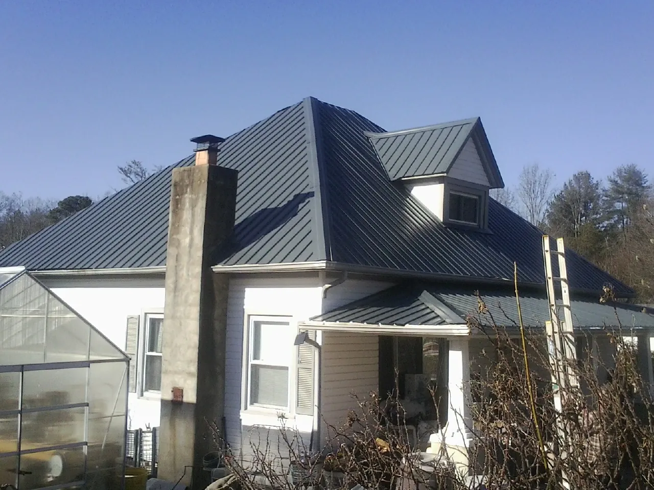 Dark blue standing seam metal roof on a white farmhouse with dormer — Slate & Tile Roof Repair by Roofing Brothers in Oceanside
