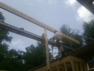 Carpenter setting a ridge beam over a new addition frame — Ice Dam Removal by Roofing Brothers in Oceanside