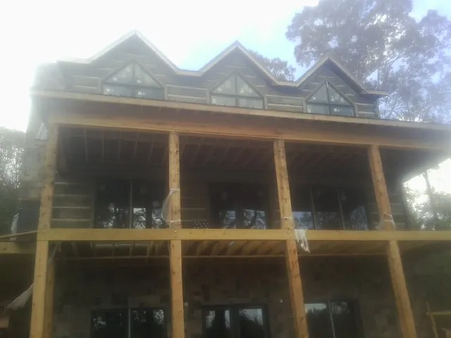 Dormers and porch framing on a large log home under construction — Roof Coating work by our crew in Oceanside
