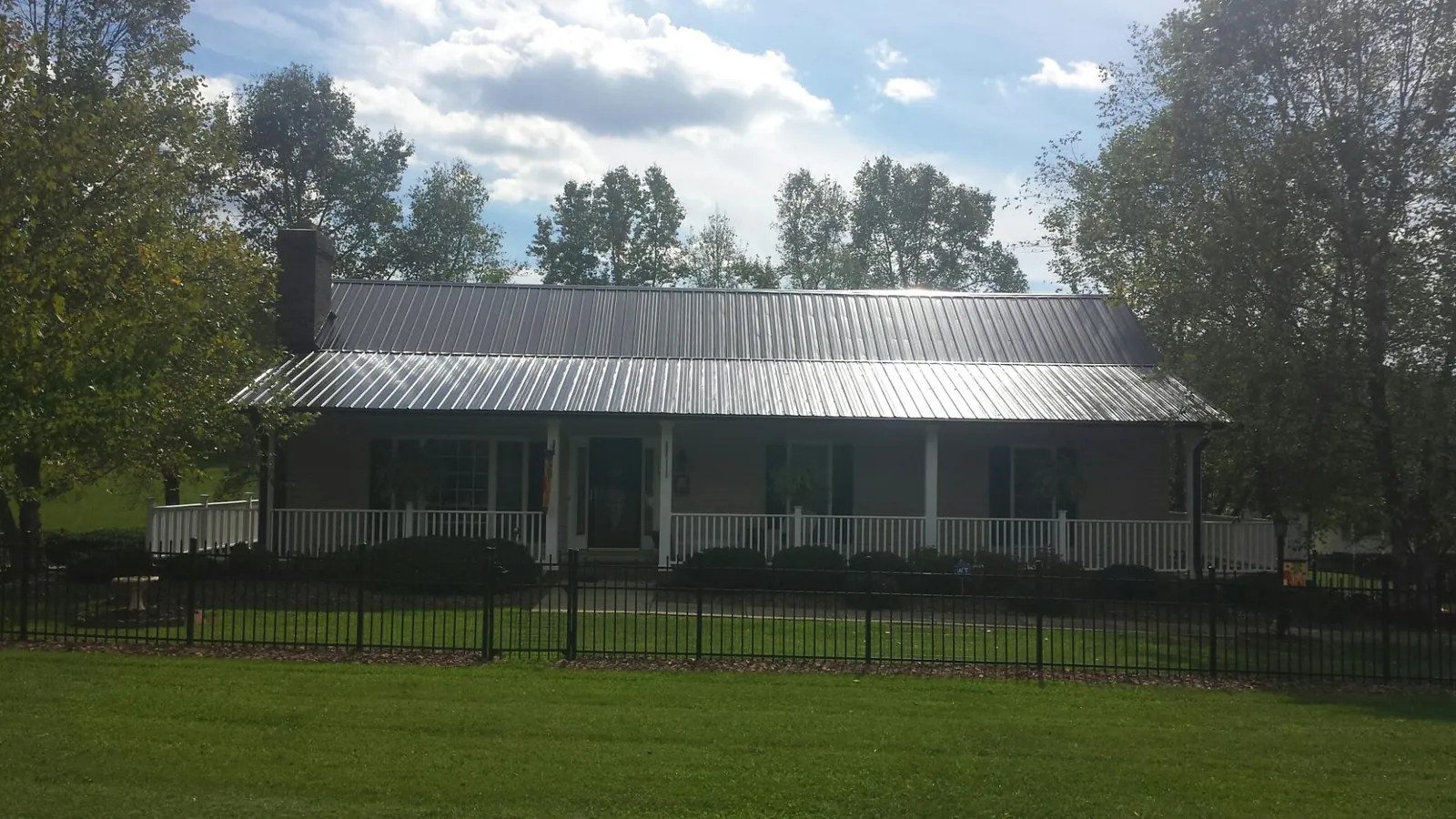Gray metal roof on a brick ranch with a full width front porch — Gutter Guard Installation work by our crew in Oceanside